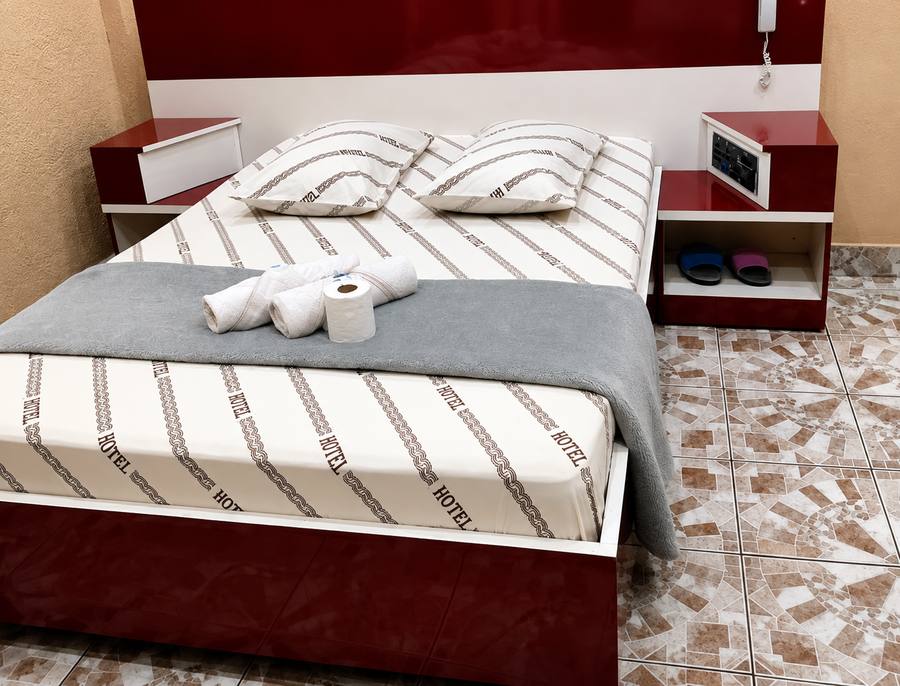Cama de casal arrumada com toalhas, criados-mudos e telefone