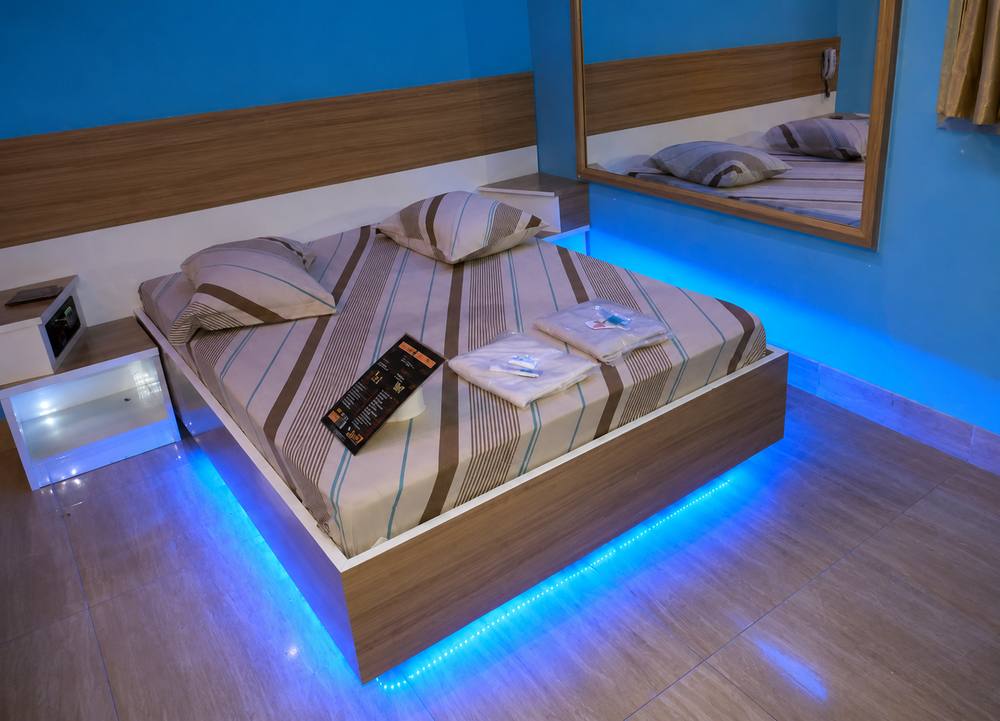Quarto com cabeceira de madeira, espelho e iluminação de cabeceira