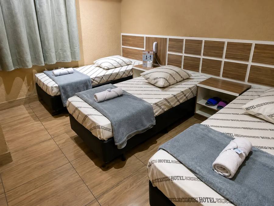 Quarto triplo com três camas de solteiro arrumadas lado a lado